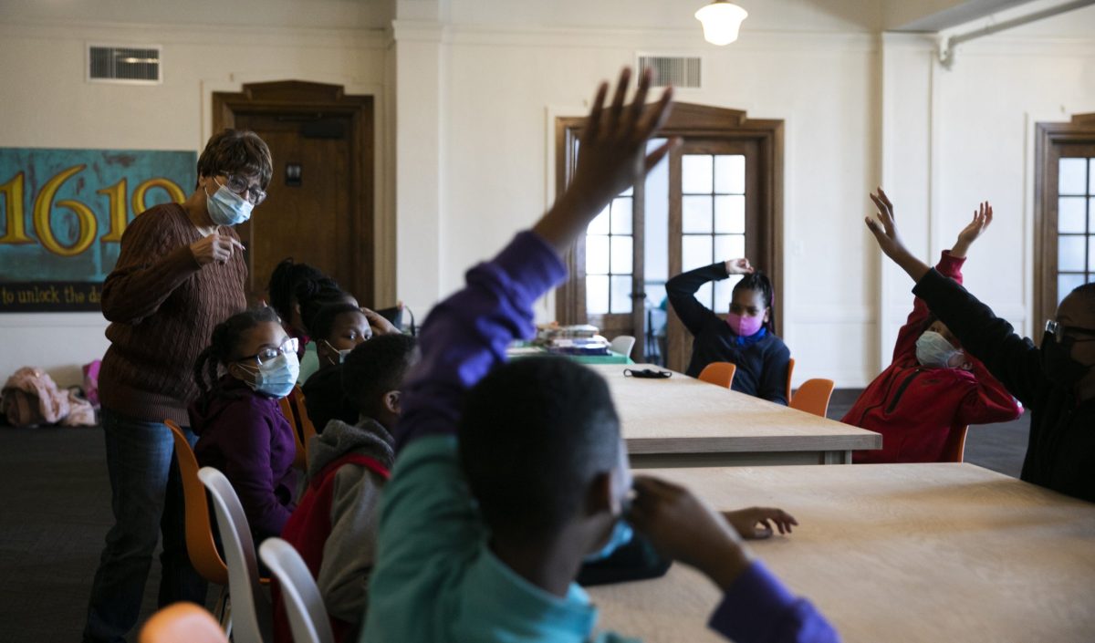 Students raise their hands during a discussion of poetry at the 1619 Freedom School.