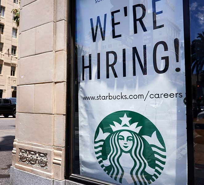 A 'We're Hiring!' sign is displayed at a Starbucks. Wages rose across all racial groups in the first 3 months of 2021.