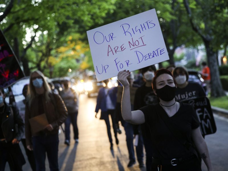 A woman with short, reddish brown hair, wearing a black face mask, holds a handmade sign that says "Our Rights Are Not Up for Debate" during a protest outside the home of U.S. Associate Supreme Court Justice Brett Kavanaugh in Chevy Chase, Maryland, on May 11.