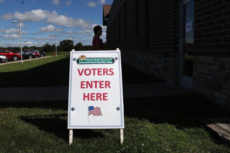 A Voters Enter Here sign sits outside of a polling place as a voter arrives to cast a ballot.