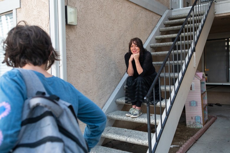 Beth Petersen sits on the stairs with her chin resting on her folded hands as she watches her son leaves for the school bus.